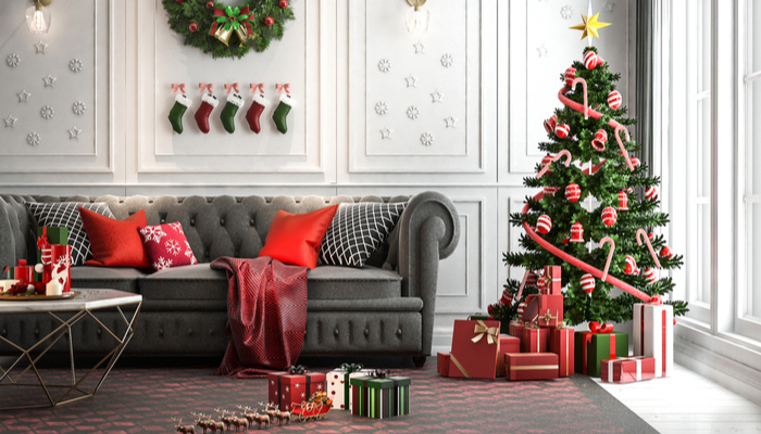 white modern classic style living room with a christmas tree with red green and white presents under it and socks decoration and red pillows on the black couch