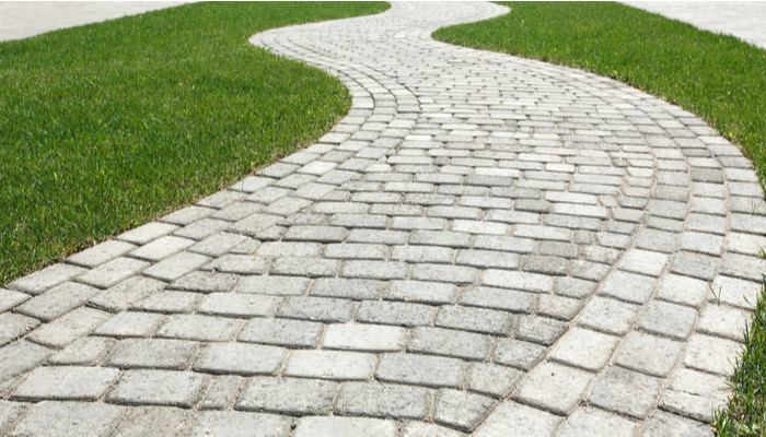 Curved path for walkway or driveway in the shape of a wave on the grass in a lawn paved with tiles of different shapes
