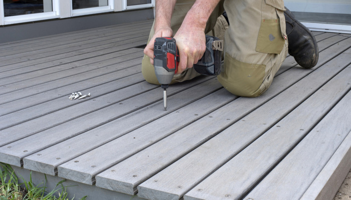 Man fixing composite gray deck with a screw gun