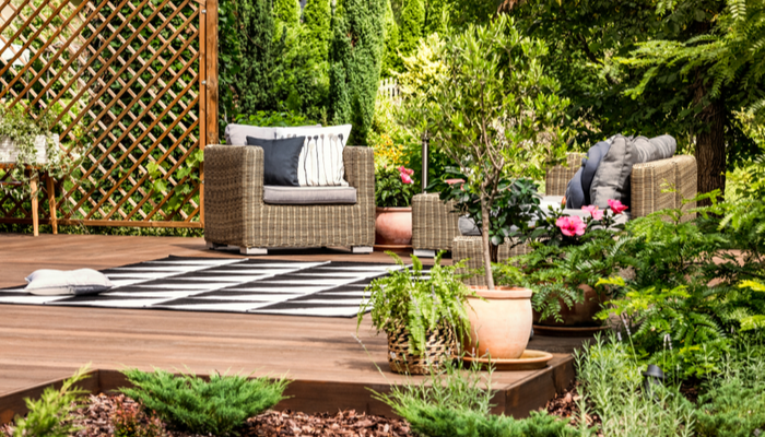 Beautiful deck on a garden with furniture on a terrace decorated with plants, bushes, flowers and trees
