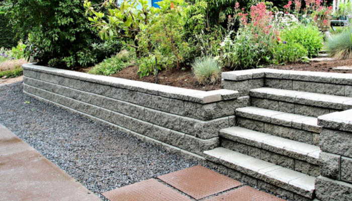 Beautiful closeup view of a staircase incorporated into a block retaining wall with flowers and different kinds of plants with steps leading into existing landscaped garden