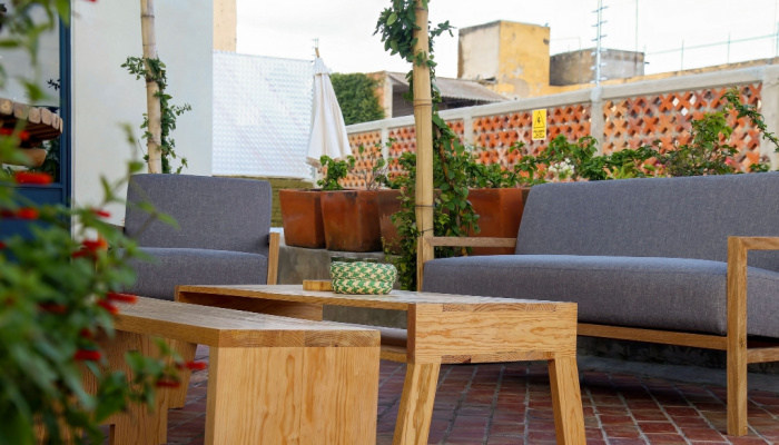 Outdoor living room with couch, comfy cushions, throw pillows, love seat, chairs and coffee table. Backyard with greenery