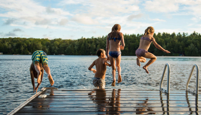 Kids jumping into the lake on a sunny day