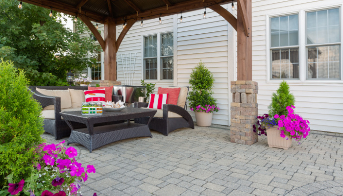 Exterior patio and summer living space with a covered gazebo, colorful petunias and comfortable seating