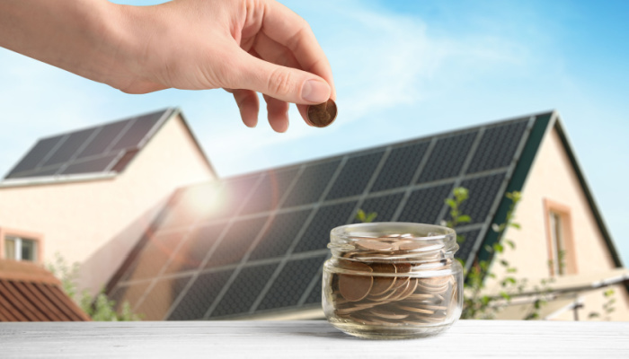 Woman contributing to savings jar with house featuring rooftop solar panels
