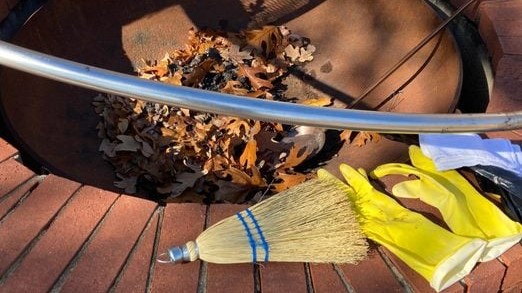 outdoor fire pit with brush and yellow gloves
